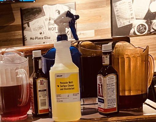 Four open beverage pitchers sharing space with commercial cleaning product.