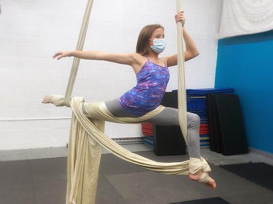 A student demonstrates a variation on a split balance on the aerial silks