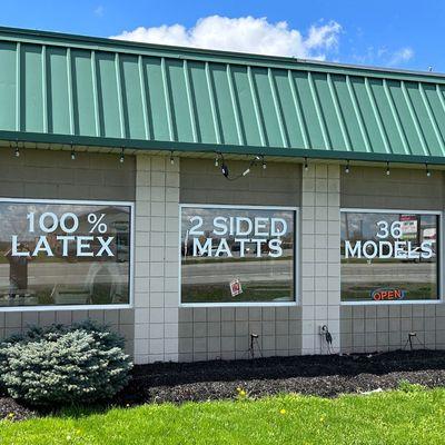 Exterior windows of the mattress store with lettering for Latex Mattresses, Two-Side Mattresses, and Custom Size