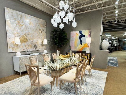 Elegant dining room at Noel Furniture featuring a sleek glass table, luxurious dining chairs, and stylish art and decor.