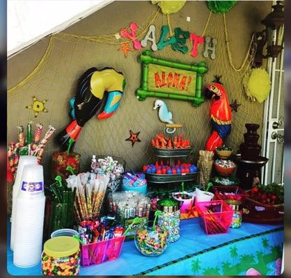 Luau candy table with chocolate fountain and fruit.