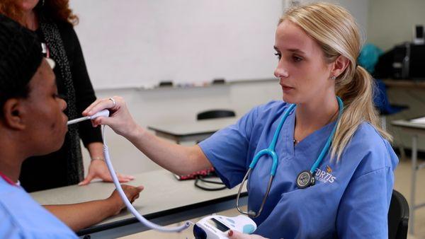 Medical Assisting student taking classmates temperature