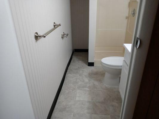 The same bathroom after putting in new drywall, bead board, new vinyl floor, caulk, paint, trim, toilet, vanity etc.