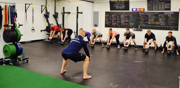 Coach Jay works to refine the set-up of the kettlebell swing during Team 360 class