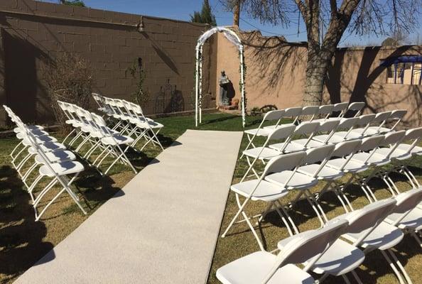 Folding chairs, carpet runner and arch set-up by Enchanted Occasions Event Rentals