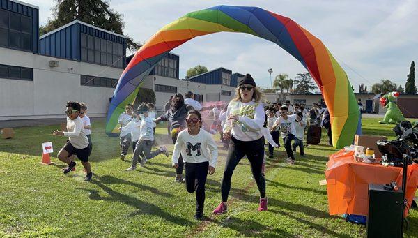 Principal runs with students in the annual PTA Color Run fundraiser