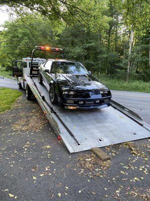 Car on flatbed with boards still on ground to raise car up just enough.