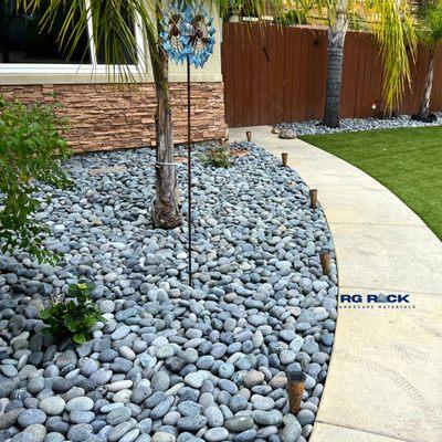 Level up your front yard: Black beach pebbles, size 2-3, offer effortless elegance and easy upkeep. Enhance your landscape now!