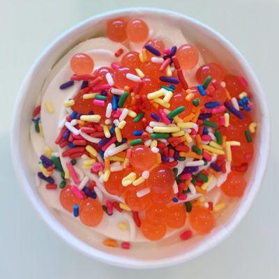 Strawberry yogurt with strawberry popping pearls and rainbow sprinkles