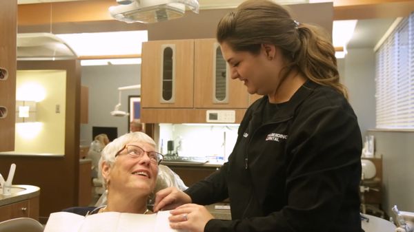 Patient in chair next to dental assistant