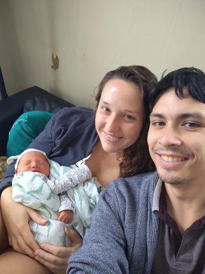 Sarah and Matthias cuddle with newborn Henry in their living room.