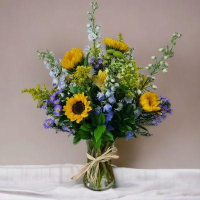 Fields of Europe for Summer - A pretty mix of sunflowers, blue delphinium, yellow alstroemeria, purple montecasino solidago and greenery