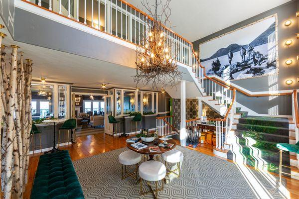 Entryway to the Bayview Hotel, with sitting area under warmly-glowing, branch-covered chandelier next to doorway to sitting area and stairs