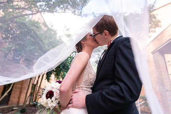 Carolyn & Charles wedding portrait kissing outside of Our Lady of Lourdes Catholic Church.