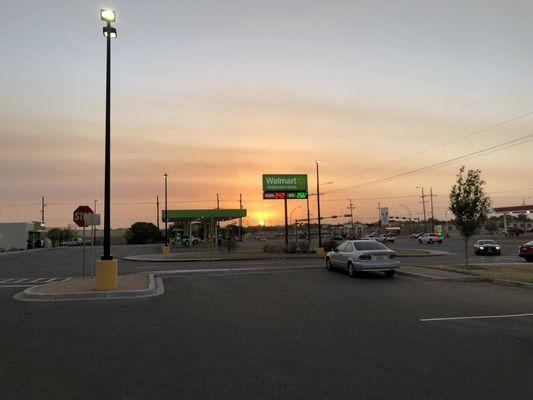 Sunset behind Walmart Neighborhood Market fuel station sign.