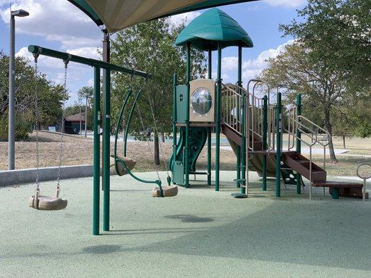 Swings and play set covered by overhead shade