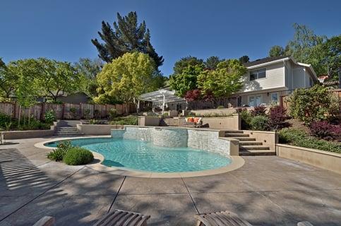 Backyard swimming pool surrounded by stamped concrete