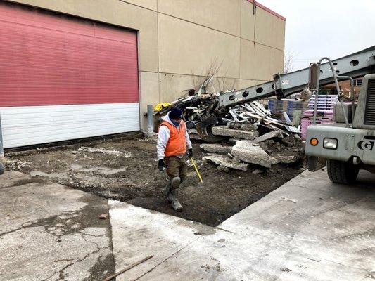 Removing section of concrete in a roofing material supply yard.