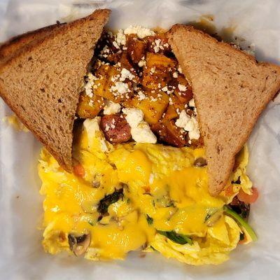 Veggie scrambler cheesy egg bowl (to-go order) with home fries and wheat toast.