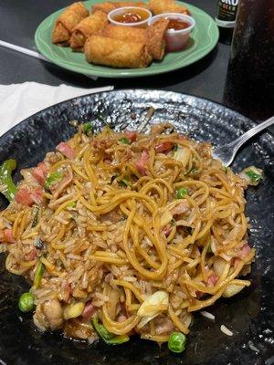 Noodles and rice stir fry and egg rolls in the back