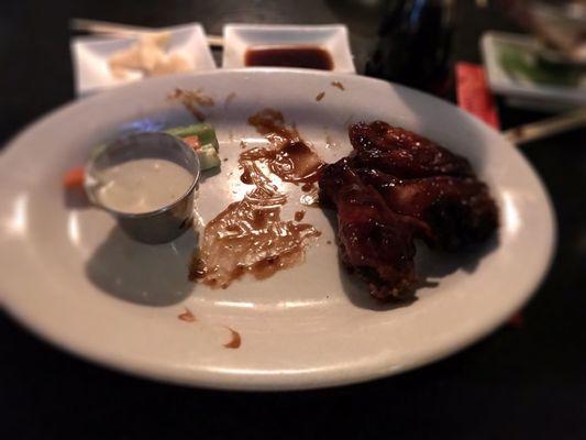 Half eaten dish of  teriyaki chicken wings