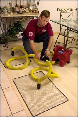 Water technician adding wood floor drying mats to save hardwood floor from water damage