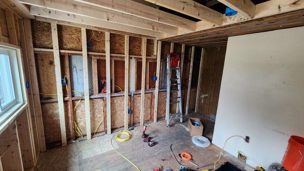 This photo shows the home after framing, during the electrical rough-in process for the restoration project