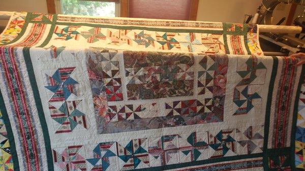 A queen-sized quilt designed from various pieces of family material. Designed by Ms. Haskett.