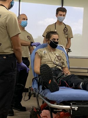 students running through a medical skills scenario, using another student as the patient