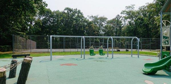 Lots of swings and a tennis court in the background