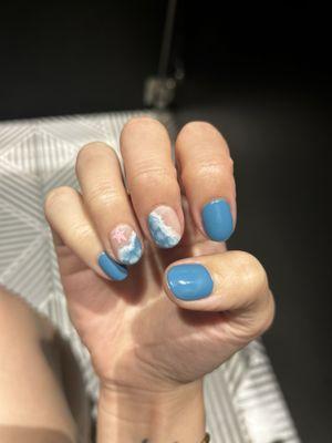 Nails recently painted blue with ocean accents on two nails.