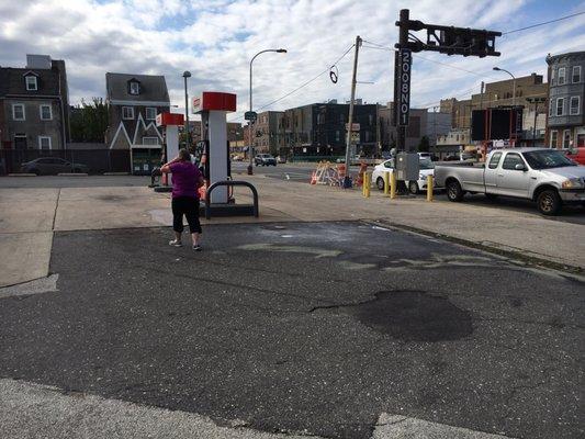 Worker placing kitty litter to soak up gas from faulty pump.