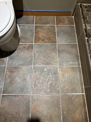 Stained gray grout floor tile by white shower's installed grout