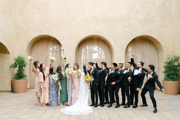 Bridal party in front of draped archways.