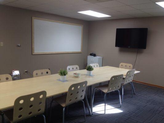 A large conference room seats up to 12 comfortably (and more if needed). Includes a large screen with HDMI input and an oversized whiteboard