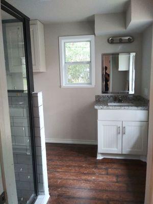 New bathroom with custom wall cabinets, New granite with underlying sink, custom shower, toilet and mirror.