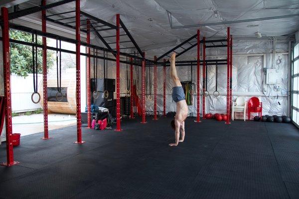 Indoor set up with monkey bars, gymnastic rings, medicine balls, rubber bands, parallettes, PVC pipe, and plyometric boxes