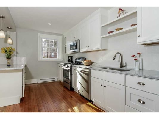 Painted white shaker cabinets, stainless steel appliances and wood floors.  White grey granite countertop and white  subway backplash tile