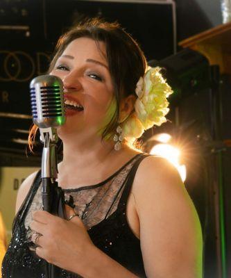 In the dimly lit ambiance of the Green Door Mocktail Bar, a jazz singer commands the stage with her soulful presence.