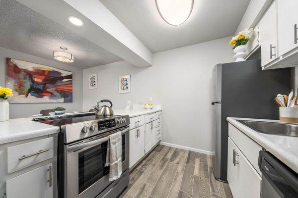 Staged kitchen and dining room with wood-inspired flooring and updated appliances