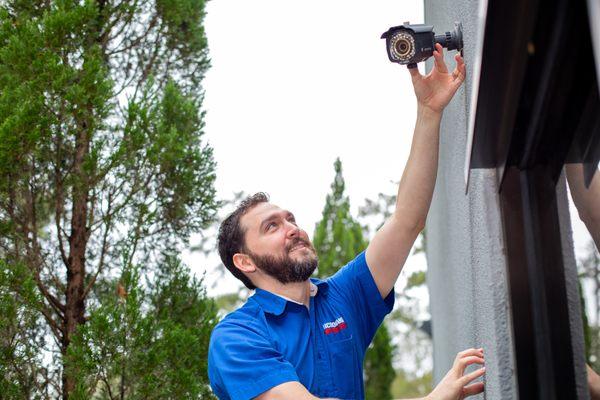 Johnathan adjusting security camera outside of building.