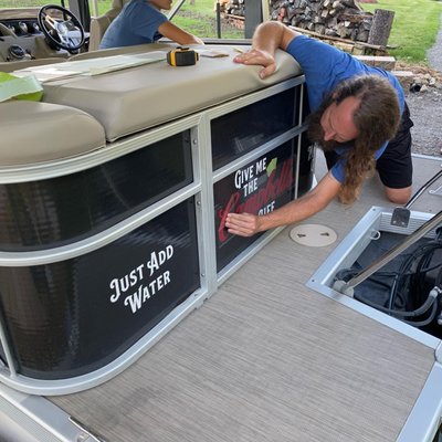 Elevating marine aesthetics! Our sign shop's skilled hands meticulously apply a vibrant vinyl wrap to this sleek boat.