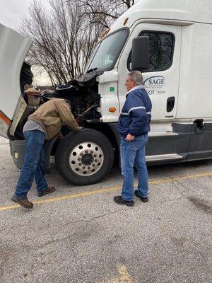 Sage faculty and student viewing front end components of truck.