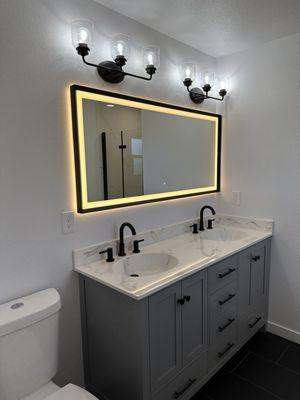 High tech lighted mirror with anti-fog feature in a modern bathroom remodel.