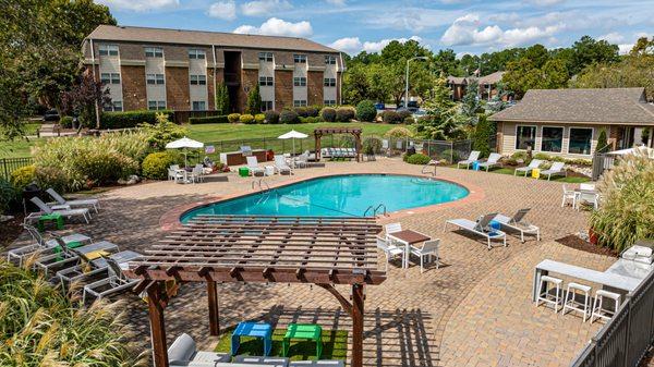 Drone shot of pool deck area next to fitness center with seating and gas grill