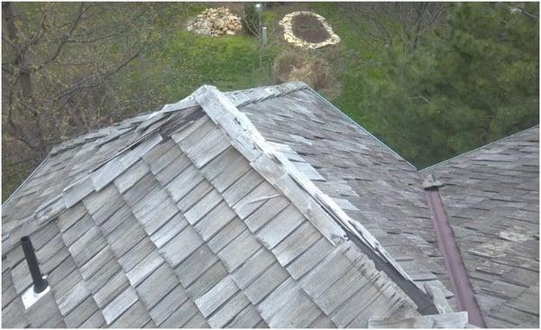 Wood cedar shake roof showing a missing ridge cap; most likely blown off by high winds.