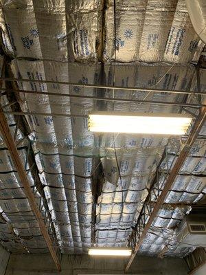 Warehouse ceiling originally had fiberglass insulation held up by a wire mesh but gravity causes it to sag = ineffective insulation.