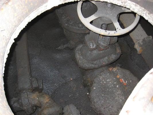 A backflow vault flooded with oily sludge from a shopping mall parking lot.