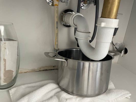 A leaky kitchen sink required a bath towel and pot to collect the water.