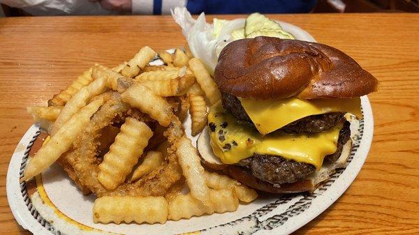 Double cheeseburger on a pretzel bun with fries and rings